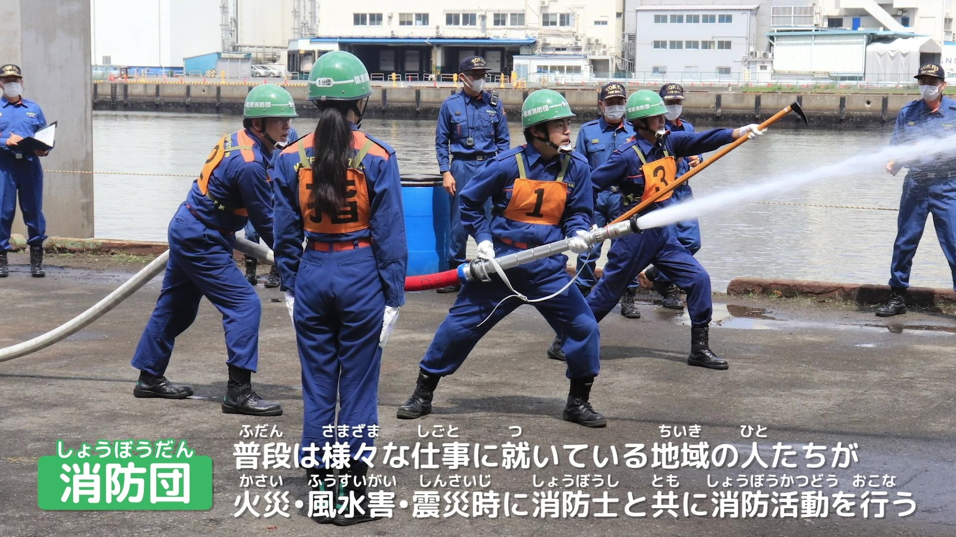 緑色のヘルメットを着用した消防団員が消火訓練を行っている写真